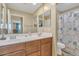 Bathroom featuring double sinks, wood cabinets, a large framed mirror, and a shower with a decorative curtain at 1923 N Cocoa Ct, Casa Grande, AZ 85122
