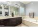 Well-lit bathroom with double vanity, soaking tub, and glass block window for added privacy at 20563 W Edgemont Ave, Buckeye, AZ 85396
