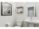Clean, modern half-bathroom with a pedestal sink, ship painting, and decorative shelving at 2313 E Hidalgo Ave, Phoenix, AZ 85040