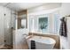 Serene bathroom featuring a freestanding tub, glass shower, and natural light from a window at 3220 W Frankfurt Dr, Chandler, AZ 85226