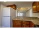 Kitchen with granite counters, wood cabinets, and white refrigerator at 3330 W Danbury Dr # E203, Phoenix, AZ 85053