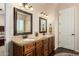 Bathroom with granite countertop vanity with double sinks, framed mirrors, dark wood cabinets, and dark wood-look tile flooring at 3614 W Phillips Rd, San Tan Valley, AZ 85144