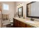 Bathroom featuring granite countertop vanity with double sinks, framed mirrors, dark wood cabinets, and dark wood-look tile flooring at 3614 W Phillips Rd, San Tan Valley, AZ 85144
