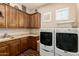 Convenient laundry room features wood cabinets, granite countertops, tile floor, plus a modern washer and dryer set at 3614 W Phillips Rd, San Tan Valley, AZ 85144