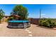 Backyard above-ground pool with a ladder and a wooden gazebo, surrounded by gravel and desert landscaping at 3614 W Phillips Rd, San Tan Valley, AZ 85144