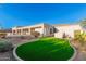 Green synthetic grass lawn and covered patio area with lush desert landscaping at 3946 N Pinnacle Hills Cir, Mesa, AZ 85207
