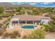 Aerial view of a home's backyard, featuring a sparkling blue pool, a BBQ area, and desert landscaping at 3946 N Pinnacle Hills Cir, Mesa, AZ 85207