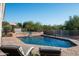 Backyard pool with stone patio, waterfall feature, lounge chairs, and desert foliage at 3946 N Pinnacle Hills Cir, Mesa, AZ 85207