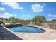 Luxurious swimming pool with stone surround, waterfall feature, desert landscaping, and a metal fence at 3946 N Pinnacle Hills Cir, Mesa, AZ 85207