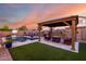 A backyard oasis complete with a swimming pool, gazebo, lounge chairs, and artificial turf at 46065 W Meadows Ln, Maricopa, AZ 85139