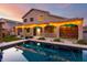 Backyard features a swimming pool, covered patio, string lights, and lush green lawn at 46065 W Meadows Ln, Maricopa, AZ 85139