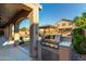 Covered outdoor kitchen featuring a built-in grill and view of the swimming pool and gazebo at 46065 W Meadows Ln, Maricopa, AZ 85139