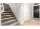 Carpeted staircase with white railings, adjacent to a door, leads upwards from the tiled floor at 46065 W Meadows Ln, Maricopa, AZ 85139