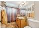 Well-lit bathroom features a wooden vanity and a shower with patterned curtain at 4726 W Indian School Rd, Phoenix, AZ 85031