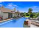 Backyard pool with tiled trim, lounge chairs, verdant grass and mature landscaping at 7526 W Cheryl Dr, Peoria, AZ 85345