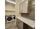 Efficient laundry room features front-load washer, dryer, grey cabinets, marbled countertops and decorative tile backsplash at 7925 S 24Th Way, Phoenix, AZ 85042