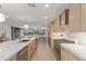 Open-concept kitchen with stainless steel appliances, wood cabinets, and a large island flowing into the living area at 8119 E San Miguel Ave, Scottsdale, AZ 85250