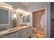 Bright bathroom with double vanity sinks, white cabinets, and an open doorway to the toilet at 10655 N 9Th St # 112, Phoenix, AZ 85020