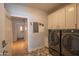 Laundry room with full-size washer and dryer, white cabinets and wood floor at 10655 N 9Th St # 112, Phoenix, AZ 85020