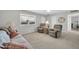 Bright living room featuring comfortable seating, neutral carpet, and large window for natural light at 10873 W Clair Dr, Sun City, AZ 85351
