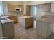 Spacious kitchen featuring a tile floor, an island, neutral cabinets and countertops, and modern appliances at 11109 W Amelia Ave, Avondale, AZ 85392
