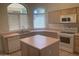 Spacious kitchen with neutral tile flooring, an island, lots of counter space, and modern appliances at 11109 W Amelia Ave, Avondale, AZ 85392