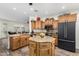 A bright kitchen has wood cabinets, granite counters, a center island, and a black refrigerator at 11312 E Newcastle Ave, Mesa, AZ 85209