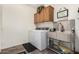 This laundry room features wooden cabinetry, a stainless steel sink, and a washing machine and dryer at 11312 E Newcastle Ave, Mesa, AZ 85209