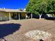 Large backyard with a covered patio, desert landscaping, and decorative rock features, perfect for outdoor living at 11653 N Hacienda Dr, Sun City, AZ 85351