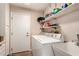 Well-lit laundry room featuring a washer, dryer, storage shelves, and utility sink at 13644 W Aleppo Dr, Sun City West, AZ 85375