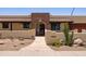 Inviting home featuring a stone arch entrance, desert landscaping, and a warm, earthy color palette at 1551 E Glencove St, Mesa, AZ 85203