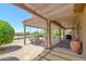Relaxing backyard covered patio with pergola, lovely stone landscape, desert plants, and plenty of seating at 16287 W Willow Creek Ln, Surprise, AZ 85374