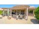 Relaxing backyard covered patio featuring outdoor seating, a desert landscape, and lush greenery at 16287 W Willow Creek Ln, Surprise, AZ 85374