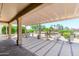 Lovely backyard patio featuring covered pergola, desert landscape, stone and concrete flooring, and lush greenery at 16287 W Willow Creek Ln, Surprise, AZ 85374