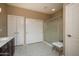 Bathroom with a shower, closet with white doors and single sink vanity with neutral-colored floor tiles at 16287 W Willow Creek Ln, Surprise, AZ 85374