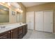 Bathroom featuring double sinks, wood cabinets, and a neutral tile floor offering functionality and style at 16287 W Willow Creek Ln, Surprise, AZ 85374