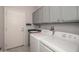 Well-equipped laundry room features a sink, ample cabinet space, and modern white washer and dryer at 16287 W Willow Creek Ln, Surprise, AZ 85374