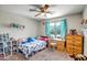 Bright bedroom featuring carpet flooring, a ceiling fan, and a window with a view of the outdoors at 17766 W Caribbean Ln, Surprise, AZ 85388