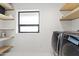 Bright laundry room with modern washer and dryer units, convenient shelving, and a large window for natural light at 1861 W Navarro Ave, Mesa, AZ 85202