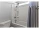Bathroom with tiled tub, modern fixture, and decorative shower curtain, with a nearby toilet at 18865 W Mescal St, Surprise, AZ 85388