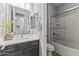 Bright bathroom featuring a modern vanity, framed mirror, and a shower-tub combo with glass doors at 18865 W Mescal St, Surprise, AZ 85388