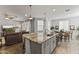 Open-concept kitchen with a granite island and stainless steel faucet, flowing into living spaces at 18865 W Mescal St, Surprise, AZ 85388