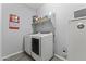 Functional laundry area with washer, dryer, storage shelves, and tile flooring at 18865 W Mescal St, Surprise, AZ 85388