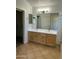 Bathroom featuring double sink vanity with bright countertop and wood cabinets, plus walk-in closet at 2092 E Smoke Tree Rd, Gilbert, AZ 85296