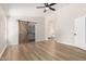 Spacious main bedroom featuring wood floors, a ceiling fan, and a sliding barn door to the closet at 20961 N 96Th Dr, Peoria, AZ 85382