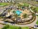 Aerial view of the community pool, lounging area, playground, and beautiful landscaping with mature trees at 2898 E Kim Dr, San Tan Valley, AZ 85143
