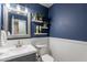 Elegant powder room featuring blue walls, white wainscoting, a modern sink vanity, and stylish wall decor at 3047 S Mandy St, Mesa, AZ 85212