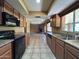 Open kitchen with wood cabinets, black appliances, and view to the living room at 3740 E Mercer Ln, Phoenix, AZ 85028