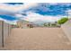 Expansive gravel backyard with block fencing and trees, offering privacy and a blank canvas for customization at 4061 N 308Th Ln, Buckeye, AZ 85396