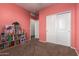 Bedroom view with pink walls, carpet flooring, and white closet doors at 4061 N 308Th Ln, Buckeye, AZ 85396